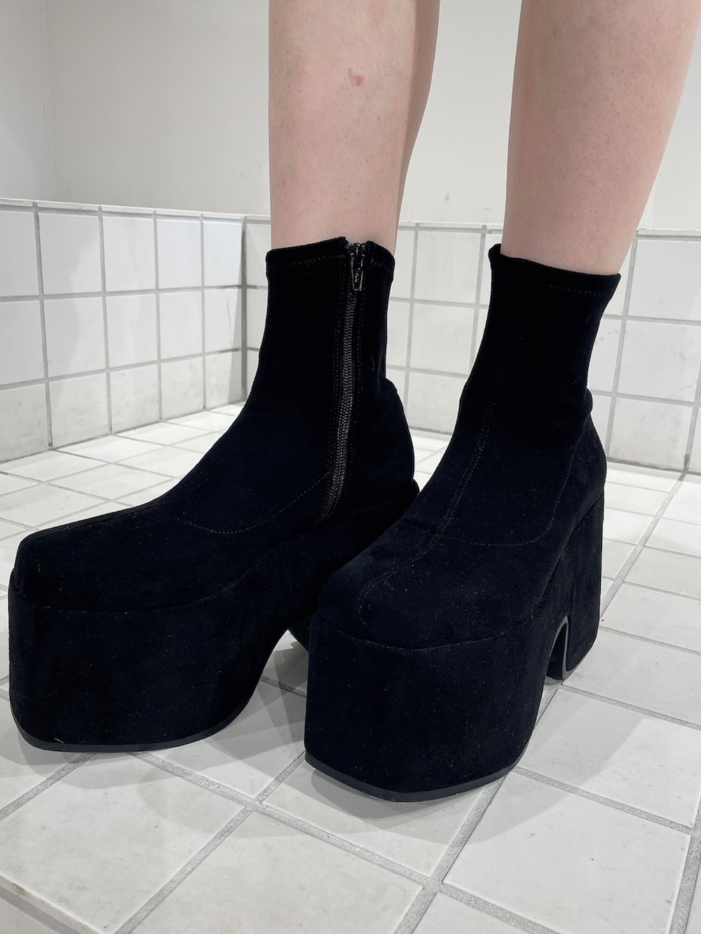 レッド系のニット/セーター、ブラック系のデニムパンツ、ブラック系のブーツを着用したレディースの秋コーディネートの9枚目の写真