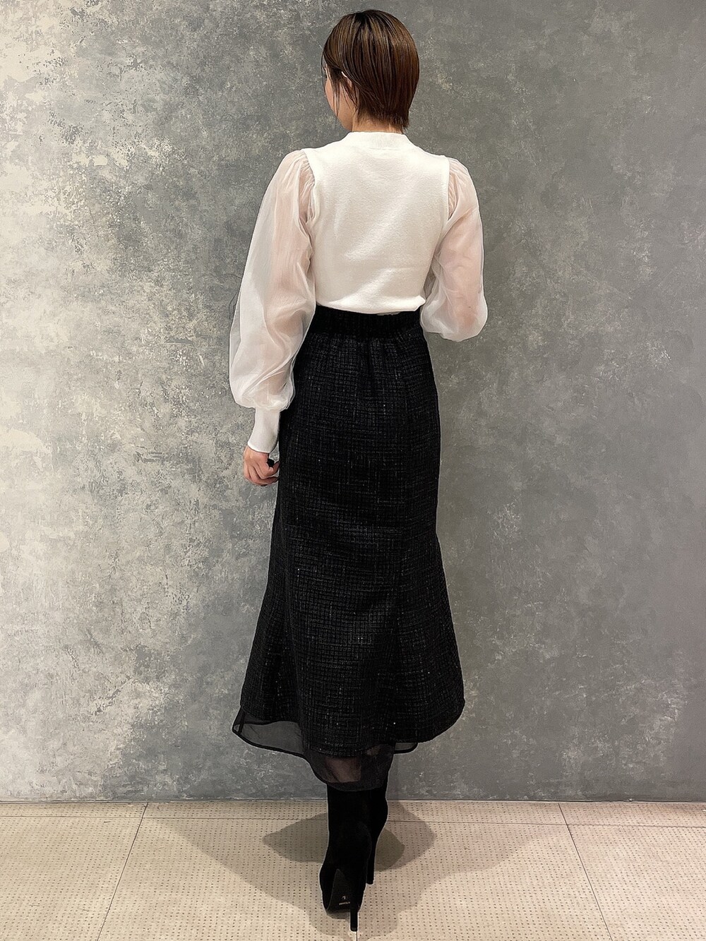 ホワイト系のダウンジャケット/コート、ブラック系のスカート、ブラック系のブーツを着用したレディースの秋コーディネートの8枚目の写真