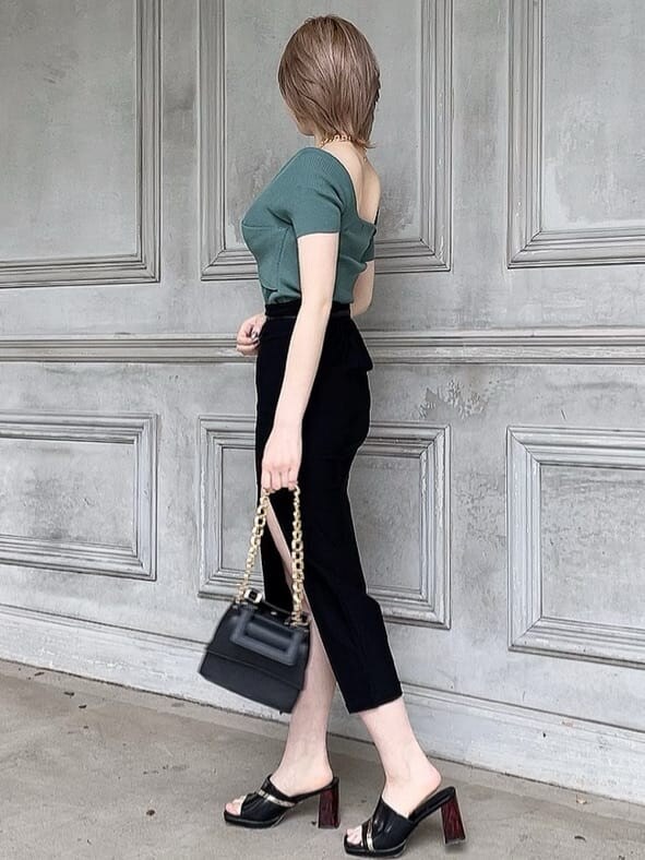 ブラック系のスカート、ブラック系のサンダル、グリーン系のニット/セーターを着用したレディースの春コーディネートの3枚目の写真