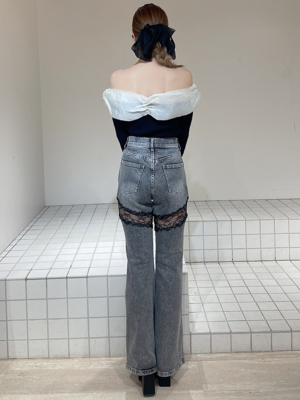 ブラック系のニット/セーター、グレー系のデニムパンツ、ブラック系のブーツを着用したレディースの春コーディネートの3枚目の写真