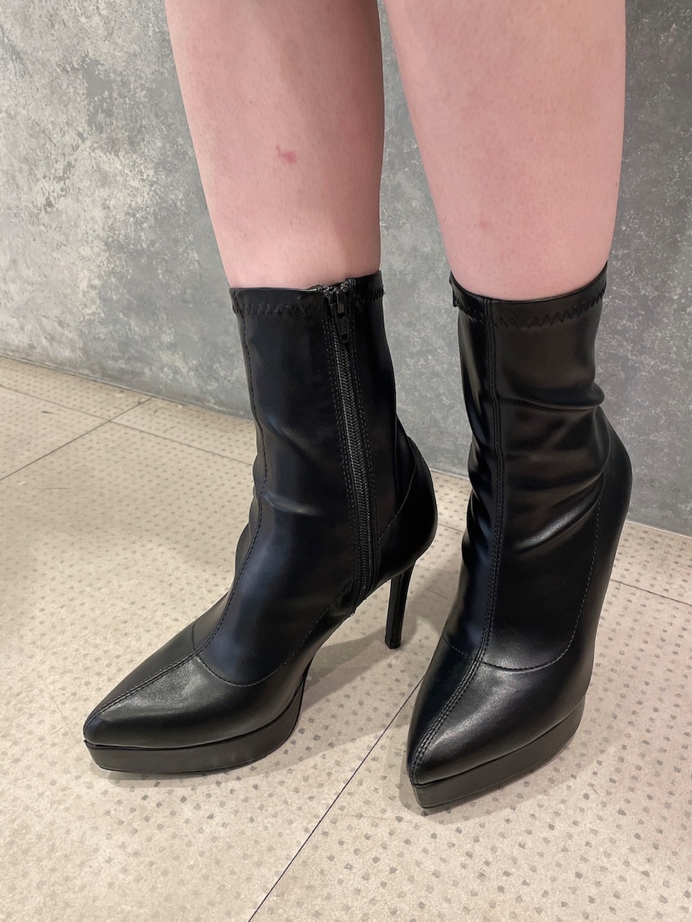 パープル系のニット/セーター、ブラック系のブーツ、ブラック系のジャンパースカートを着用したレディースの秋コーディネートの7枚目の写真