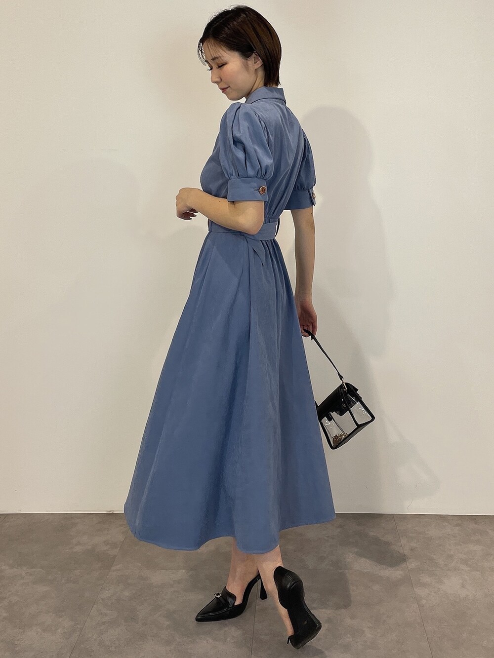 ブルー系のワンピース、ブラック系のパンプス、ブラック系のハンドバッグを着用したレディースの冬コーディネートの4枚目の写真