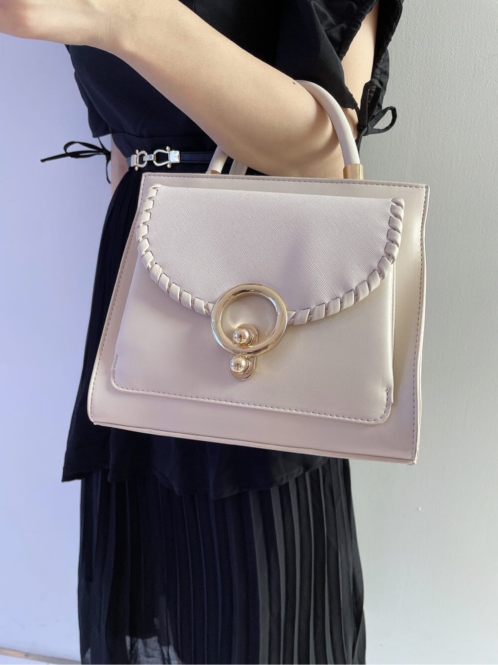 ホワイト系のハンドバッグ、ブラック系のワンピース、ベージュ系のパンプスを着用したレディースの夏コーディネートの7枚目の写真