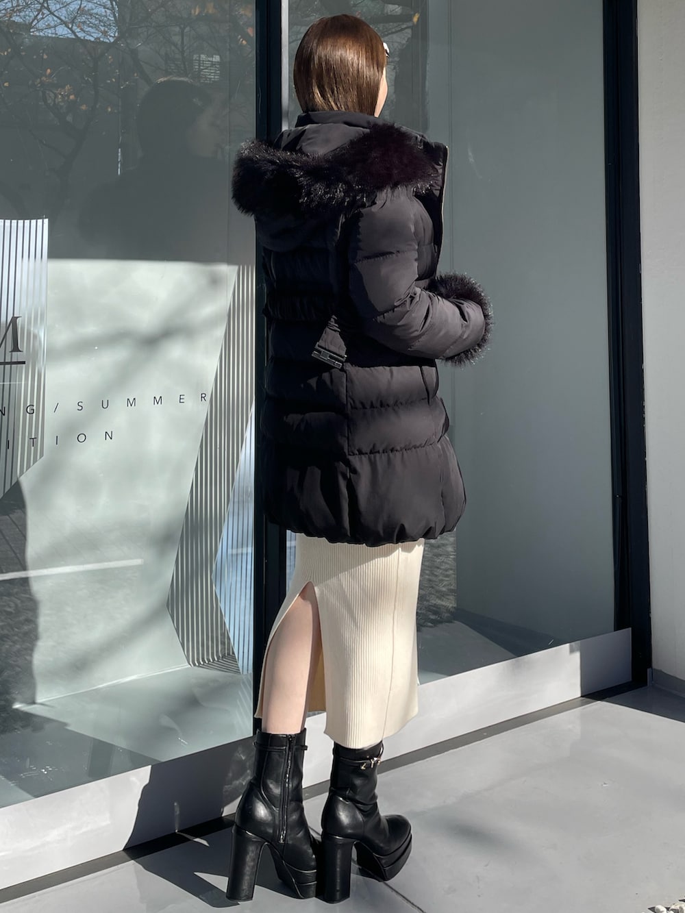 ブラック系のダウンジャケット/コート、ホワイト系のワンピース、ブラック系のブーツを着用したレディースの冬コーディネートの5枚目の写真