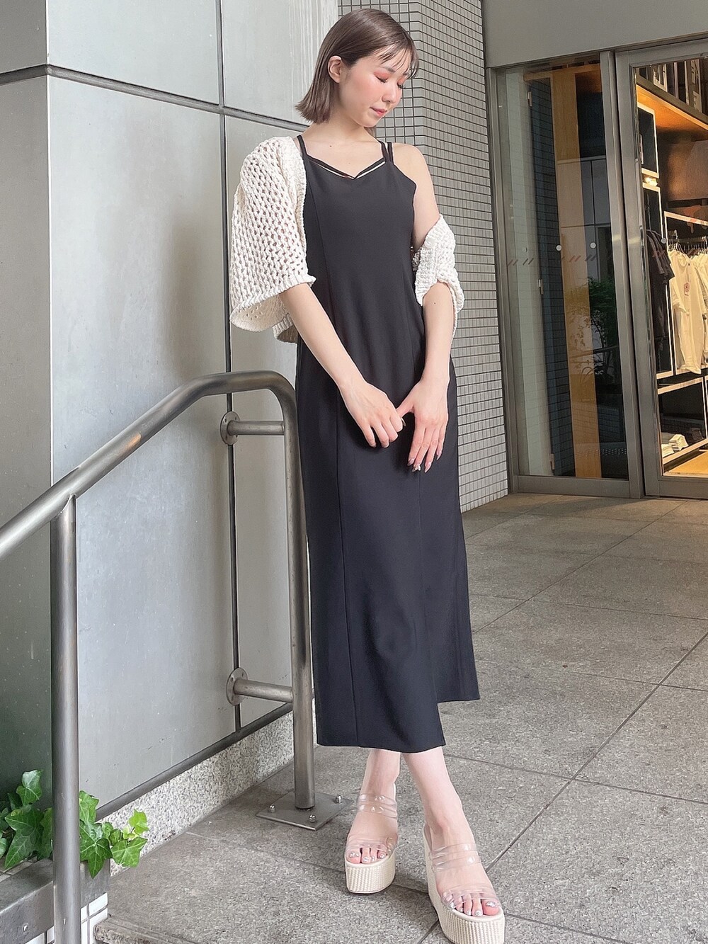 ホワイト系のカーディガン/ボレロ、ブラック系のワンピース、ホワイト系のサンダルを着用したレディースの夏コーディネートの2枚目の写真