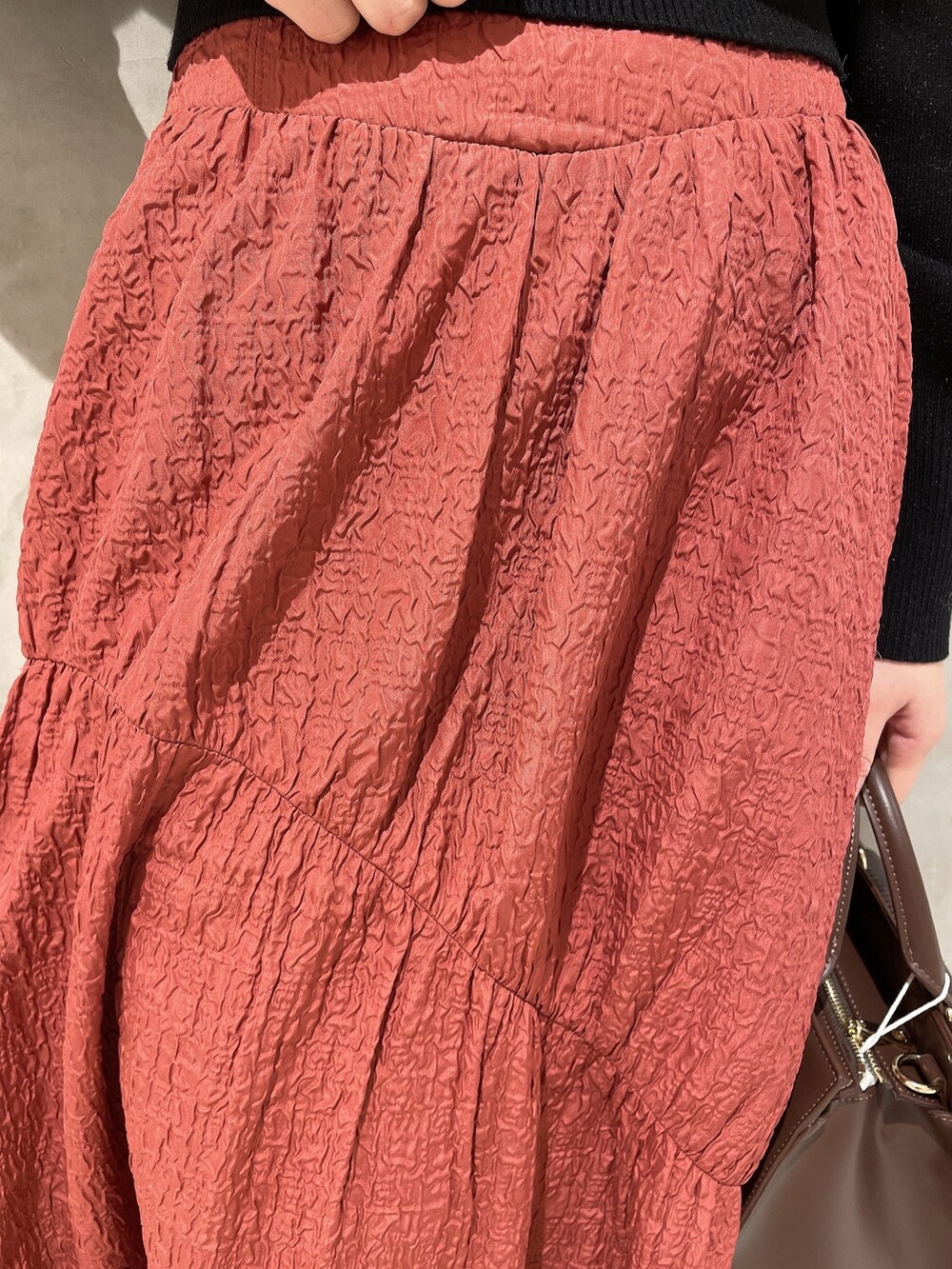 ベージュ系のダウンジャケット/コート、ブラック系のニット/セーター、ブラウン系のハンドバッグを着用したレディースの秋コーディネートの8枚目の写真