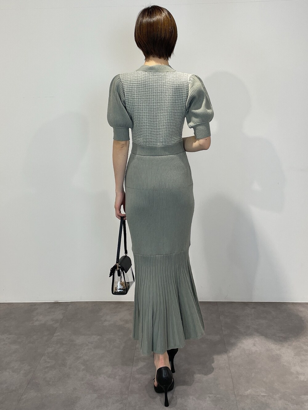 グリーン系のワンピース、ブラック系のパンプス、ブラック系のハンドバッグを着用したレディースの冬コーディネートの4枚目の写真