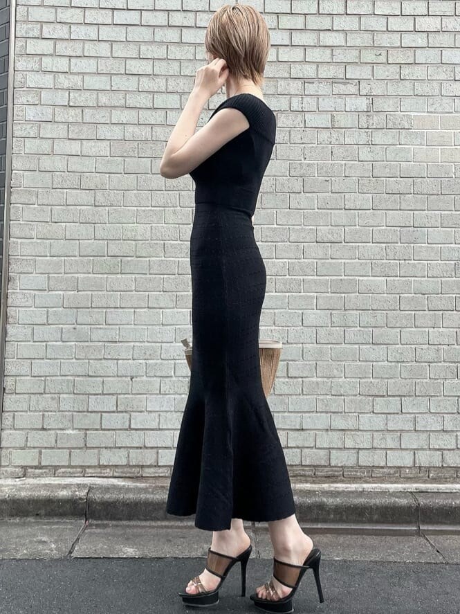 ブラック系のワンピース、ブラック系のサンダル、ベージュ系のハンドバッグを着用したレディースの夏コーディネートの2枚目の写真