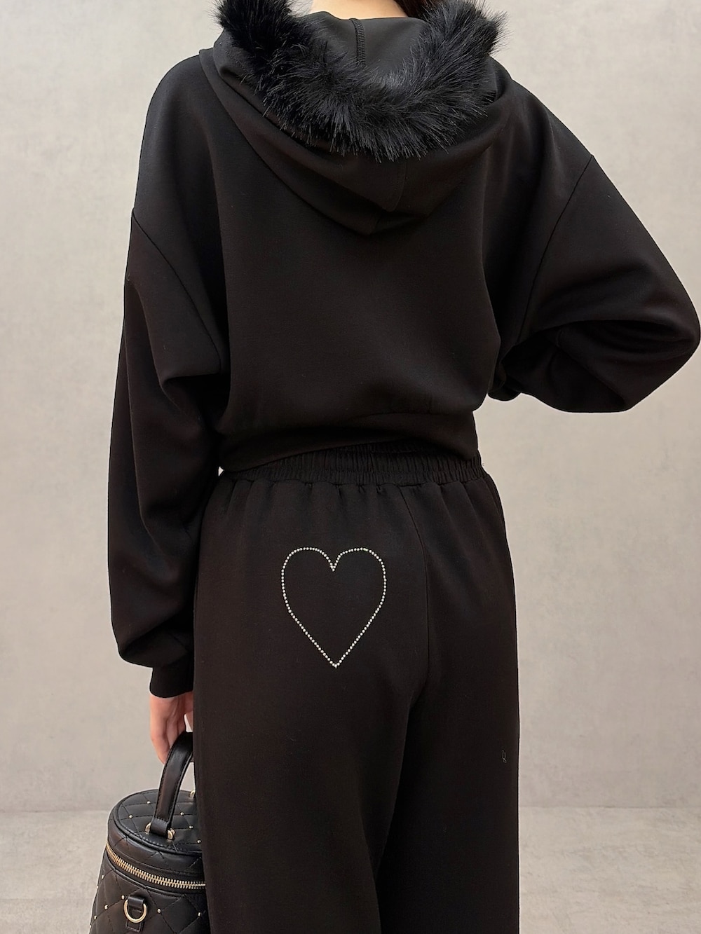 ブラック系のパーカー、ブラック系のスウェットパンツ、ブラック系のハンドバッグを着用したレディースの秋コーディネートの5枚目の写真