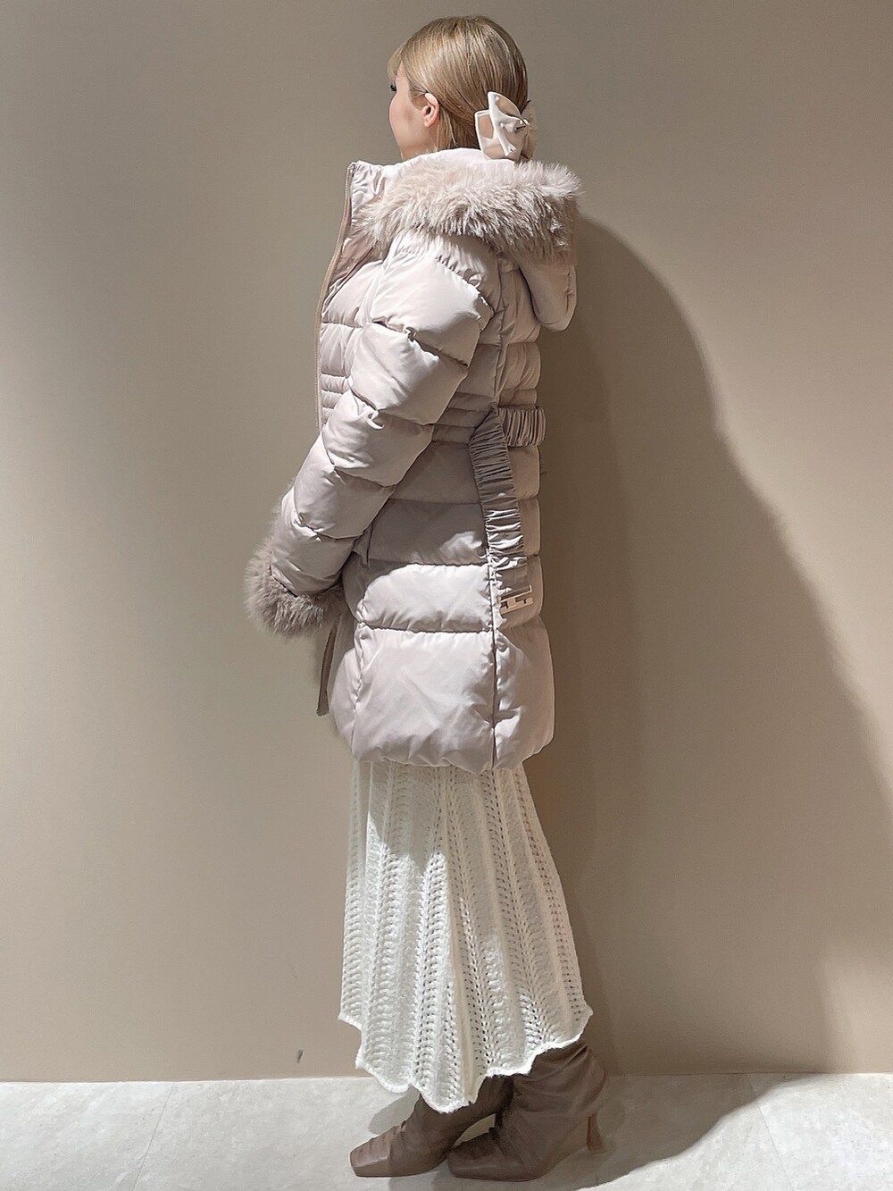 ベージュ系のブーツ、ベージュ系のダウンジャケット/コート、ホワイト系のワンピースを着用したレディースの秋コーディネートの2枚目の写真