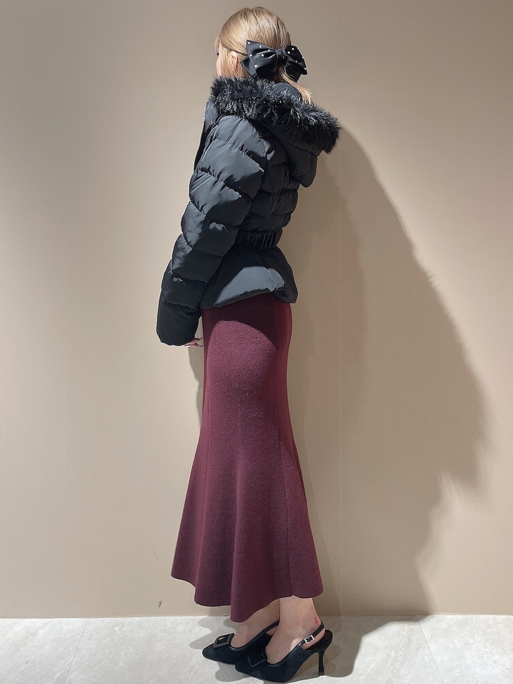 レッド系のワンピース、ブラック系のパンプス、ブラック系のダウンジャケット/コートを着用したレディースの秋コーディネートの6枚目の写真