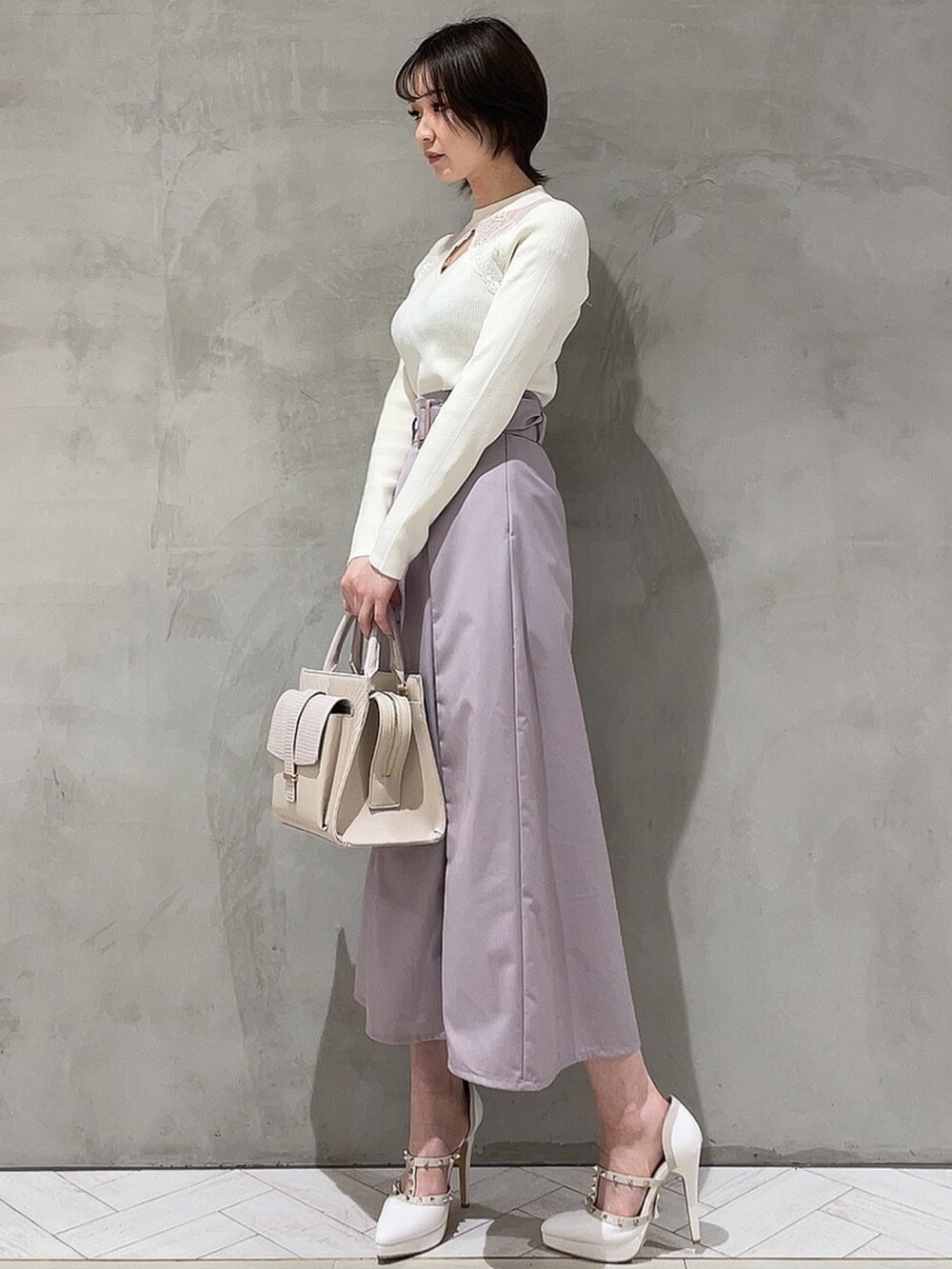 ホワイト系のニット/セーター、パープル系のスカート、ホワイト系のハンドバッグを着用したレディースの冬コーディネートの3枚目の写真