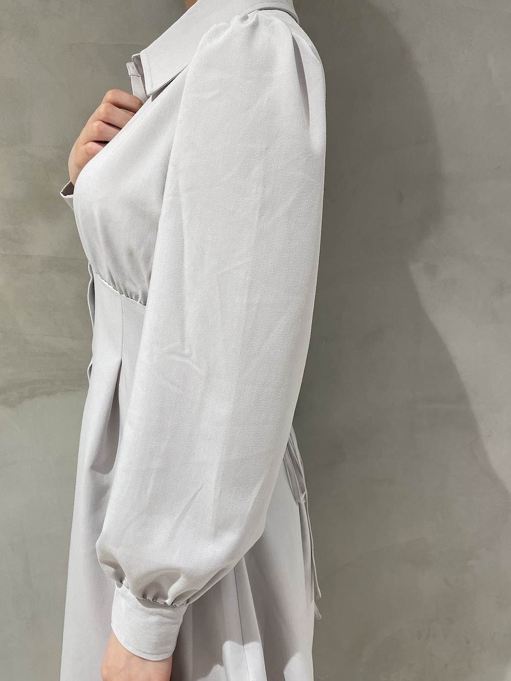 ブラウン系のハンドバッグ、ホワイト系のブーツ、グレー系のシャツワンピースを着用したレディースの冬コーディネートの4枚目の写真