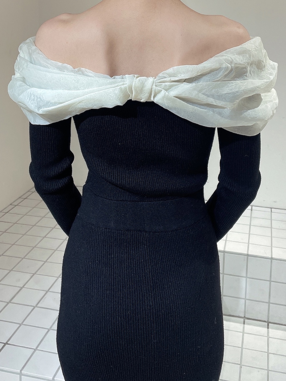 ホワイト系のハンドバッグ、ホワイト系のブーツ、ブラック系のワンピースを着用したレディースの冬コーディネートの6枚目の写真