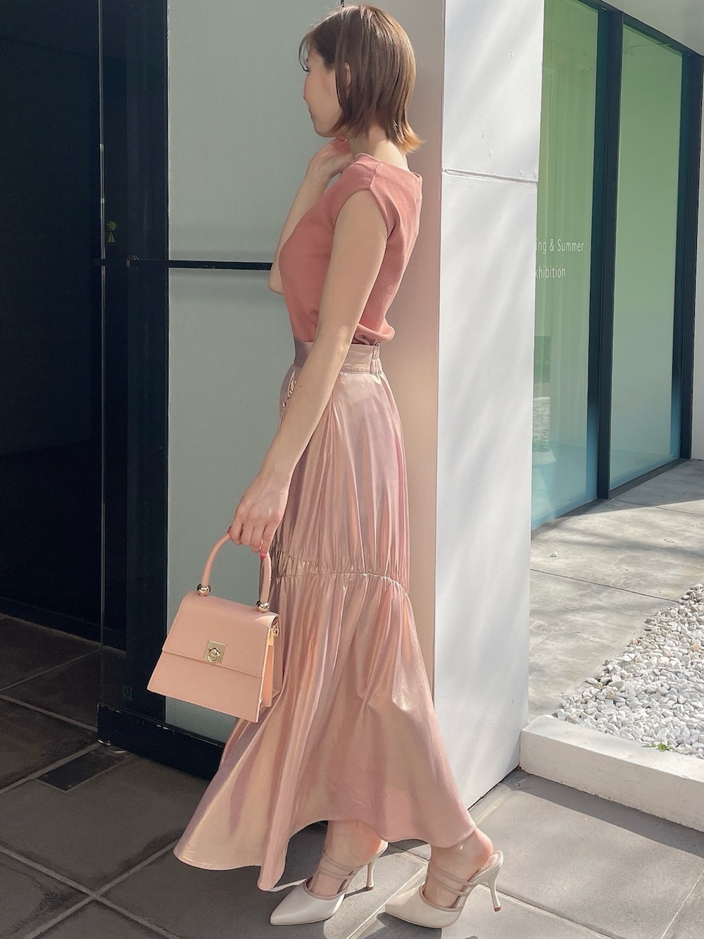 オレンジ系のニット/セーター、ゴールド系のスカート、ピンク系のハンドバッグを着用したレディースの春コーディネートの3枚目の写真