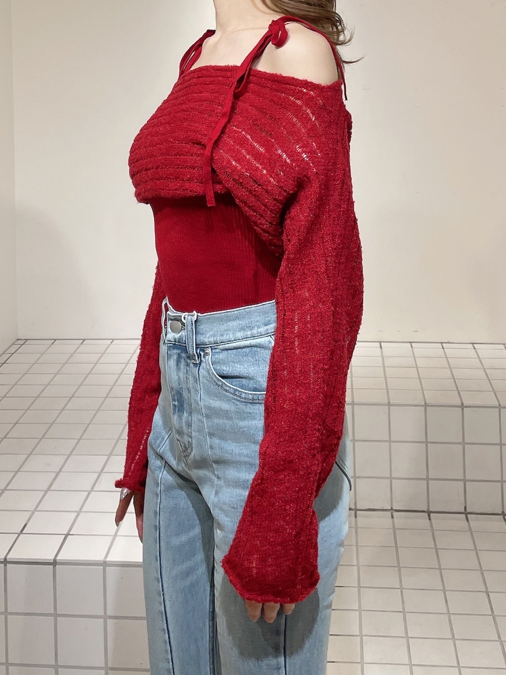 レッド系のニット/セーター、ブルー系のデニムパンツ、ホワイト系のブーツを着用したレディースの冬コーディネートの6枚目の写真