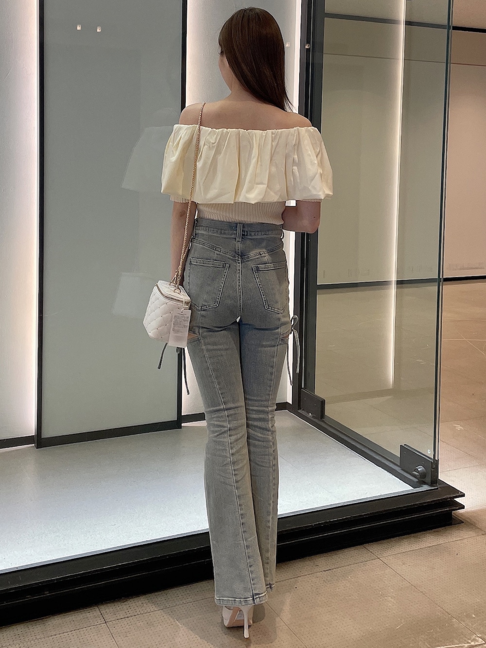ホワイト系のニット/セーター、ブルー系のデニムパンツ、ホワイト系のブーツを着用したレディースの春コーディネートの3枚目の写真