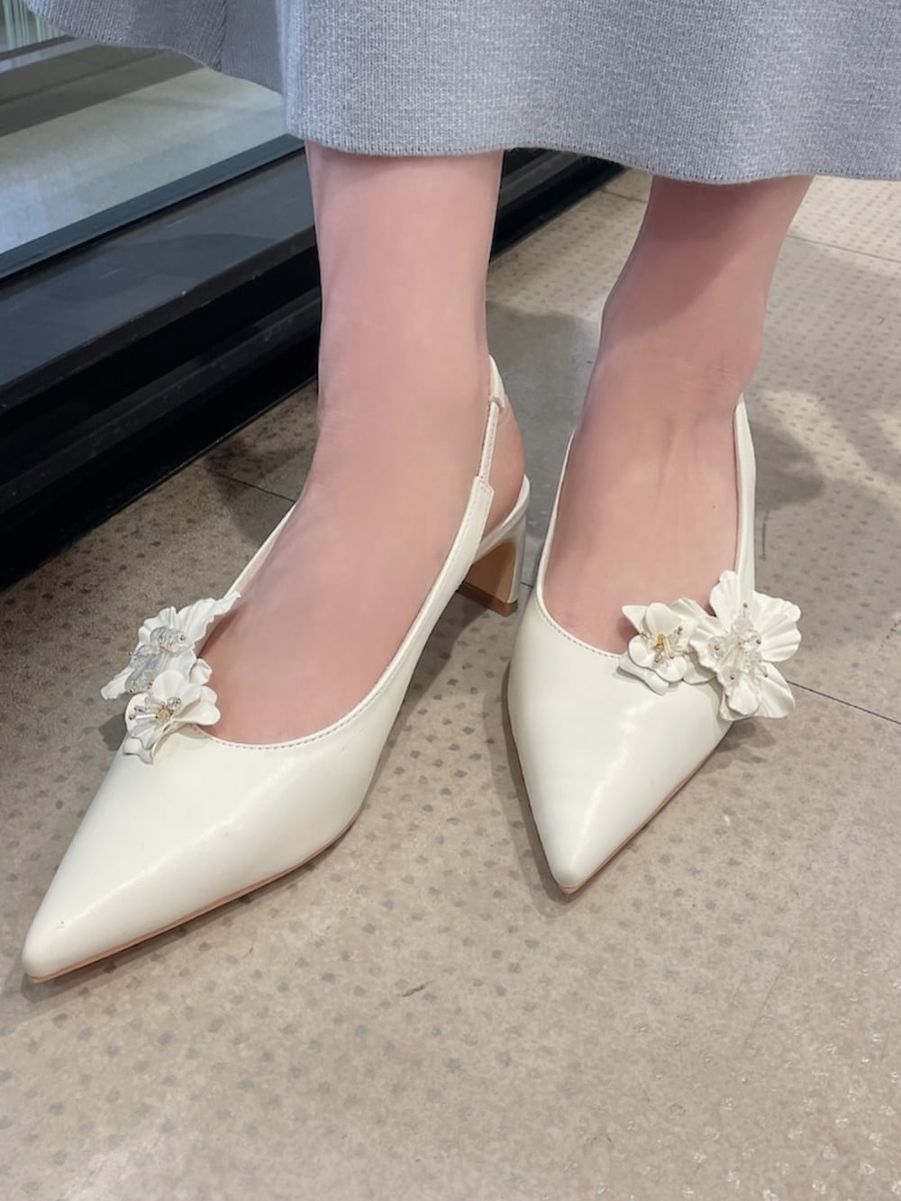 ベージュ系のカーディガン/ボレロ、ホワイト系のワンピース、ホワイト系のパンプスを着用したレディースの冬コーディネートの8枚目の写真