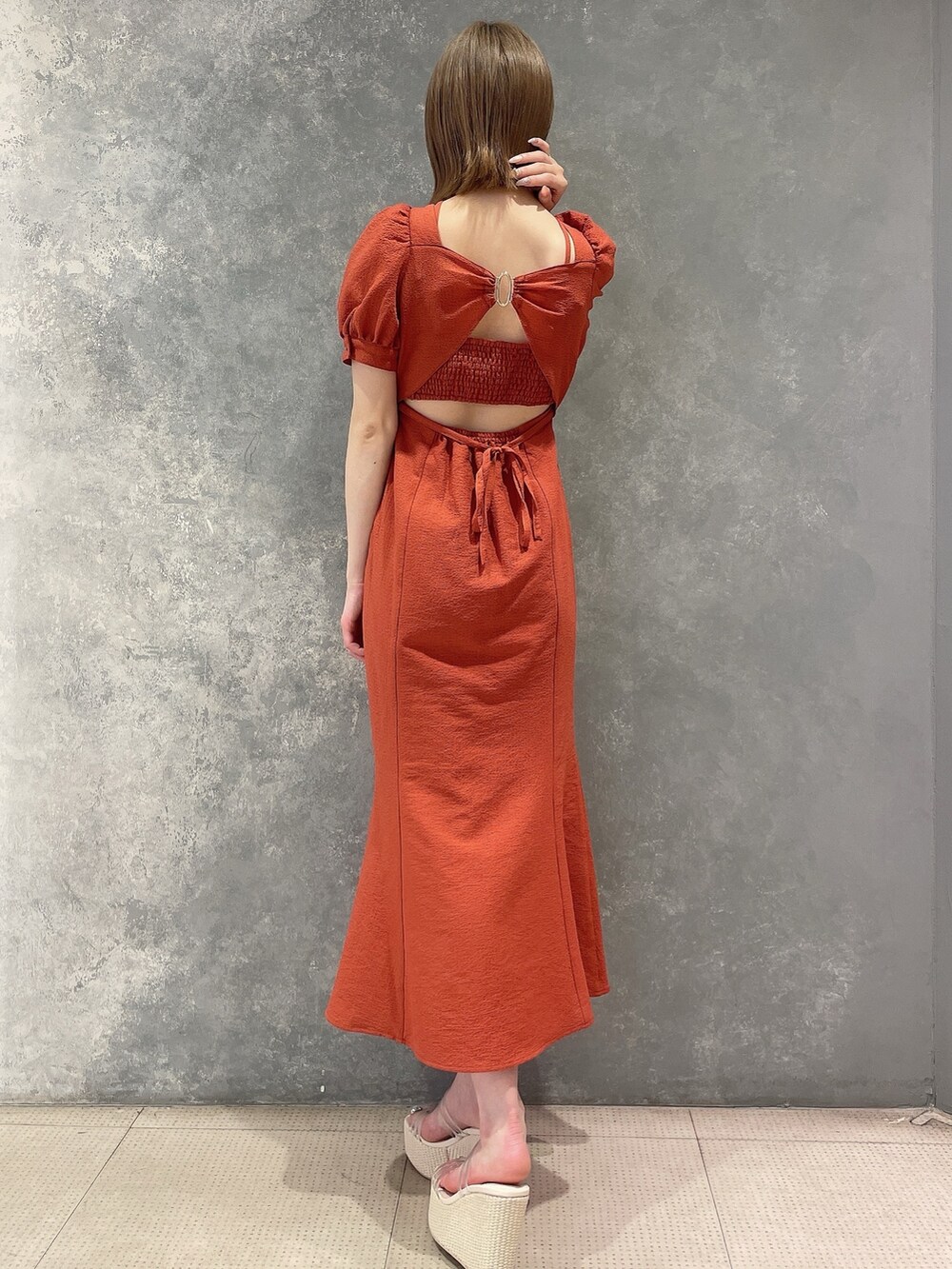 オレンジ系のワンピース、ホワイト系のサンダルを着用したレディースの春コーディネートの5枚目の写真