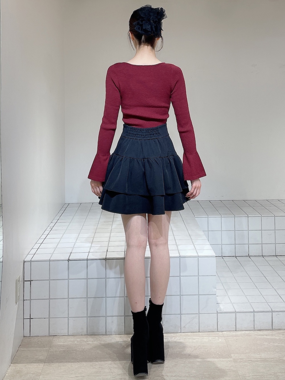 レッド系のニット/セーター、ブラック系のスカート、ブラック系のブーツを着用したレディースの冬コーディネートの4枚目の写真