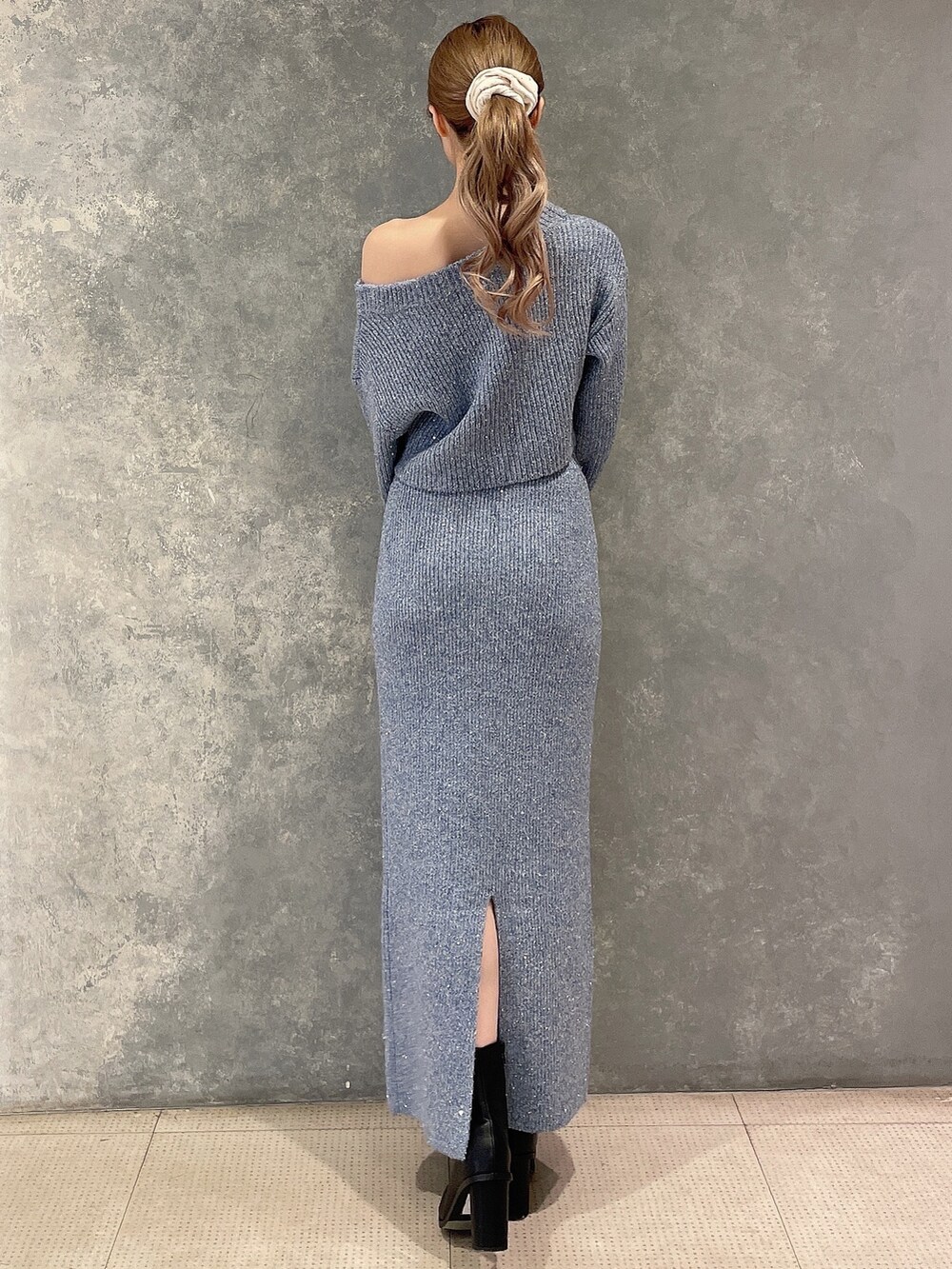 ブルー系のニット/セーター、ブルー系のスカート、ブラック系のブーツを着用したレディースの秋コーディネートの4枚目の写真