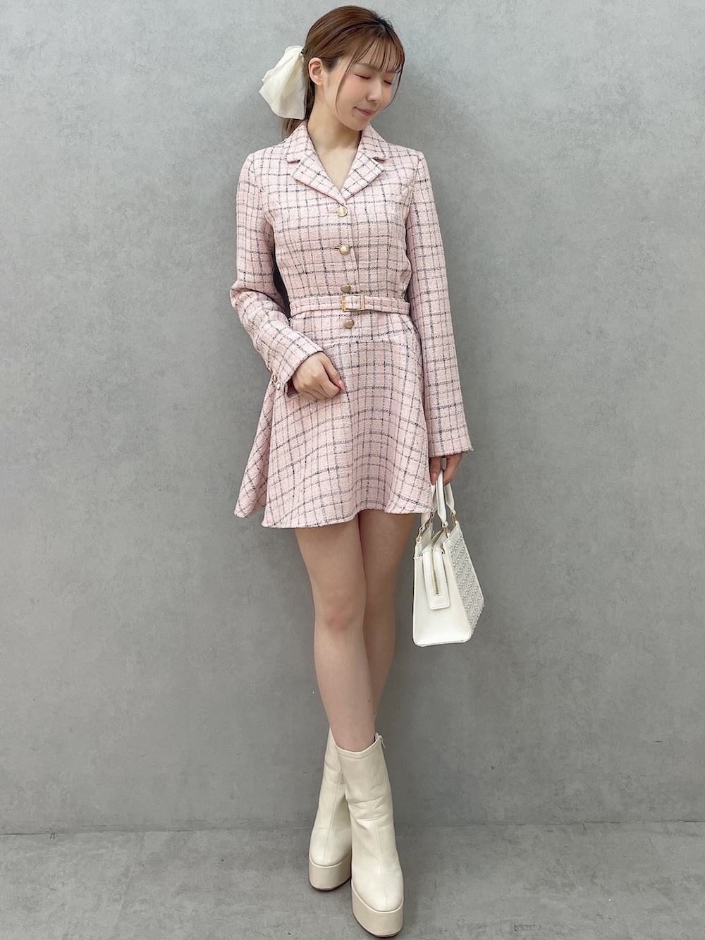 ピンク系のワンピース、ホワイト系のハンドバッグ、ホワイト系のブーツを着用したレディースの春コーディネートの2枚目の写真