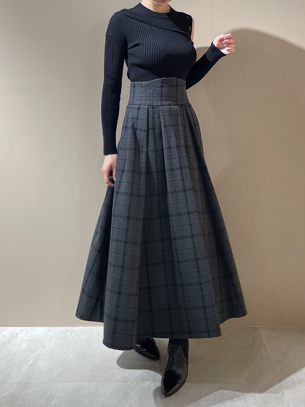 ブラック系のニット/セーター、ブラック系のスカート、ブラック系のブーツを着用したレディースの秋コーディネートの4枚目の写真