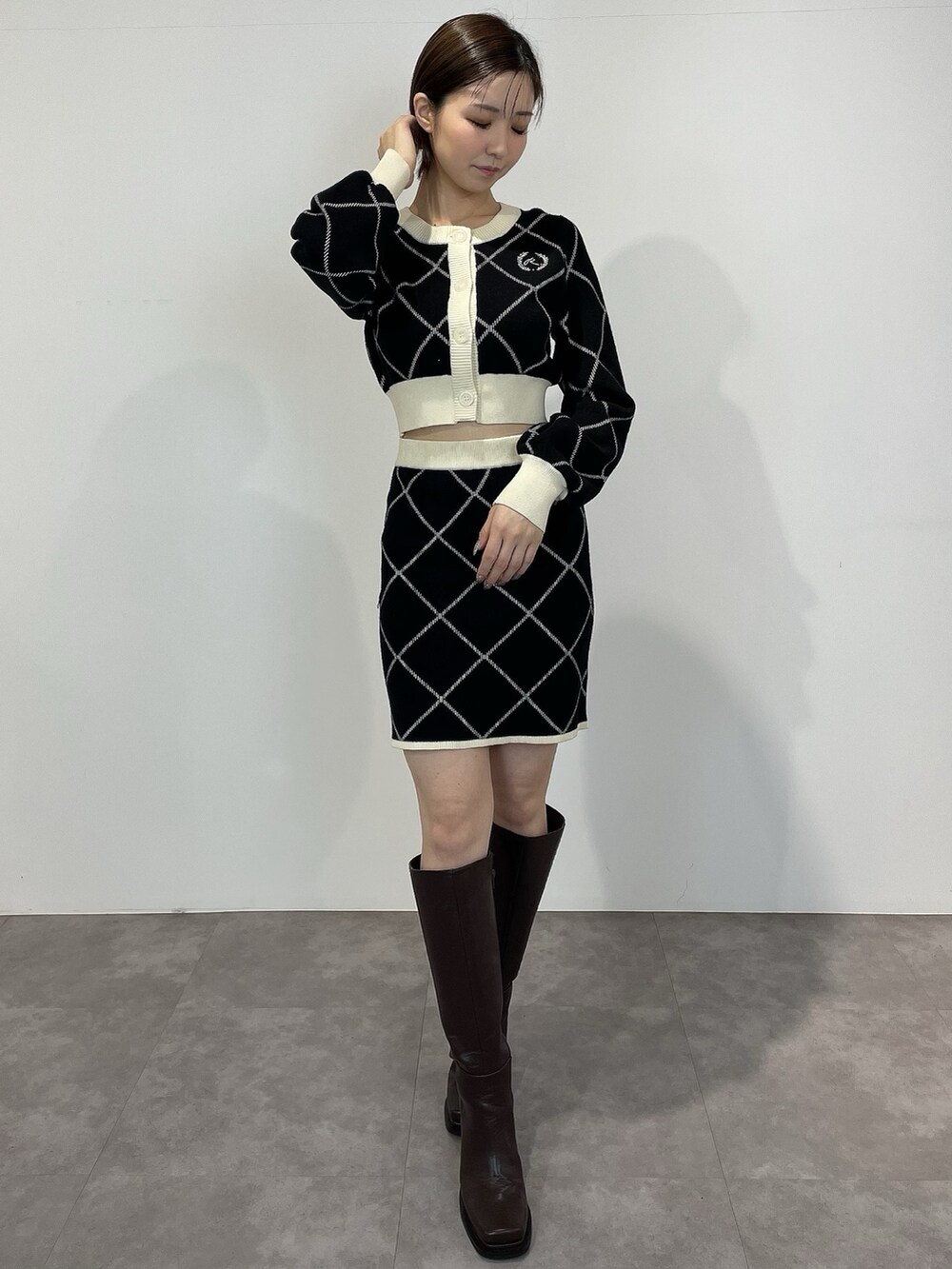 ブラック系のカーディガン/ボレロ、ブラック系のスカート、ブラウン系のブーツを着用したレディースの冬コーディネートの2枚目の写真