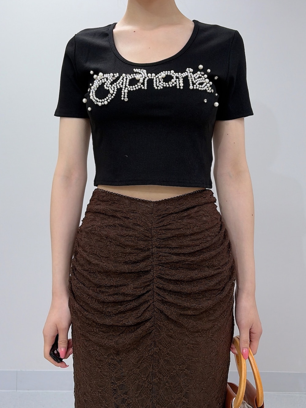 ブラック系のTシャツ/カットソー、ブラウン系のスカート、ブラウン系のハンドバッグを着用したレディースの夏コーディネートの6枚目の写真