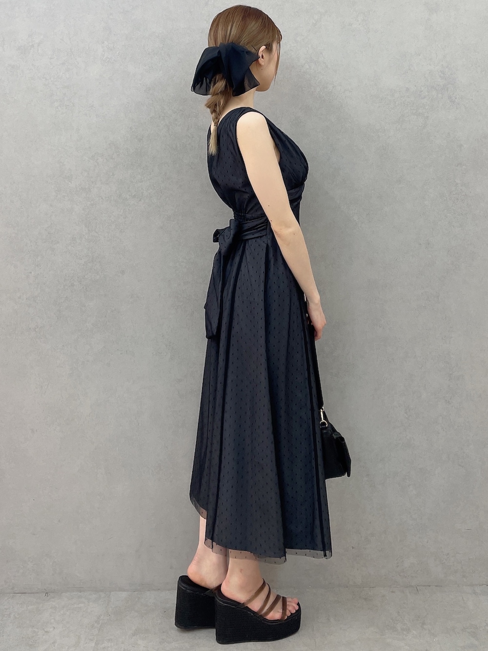 ブラック系のサンダル、ブラック系のワンピース、ブラック系のハンドバッグを着用したレディースの春コーディネートの3枚目の写真