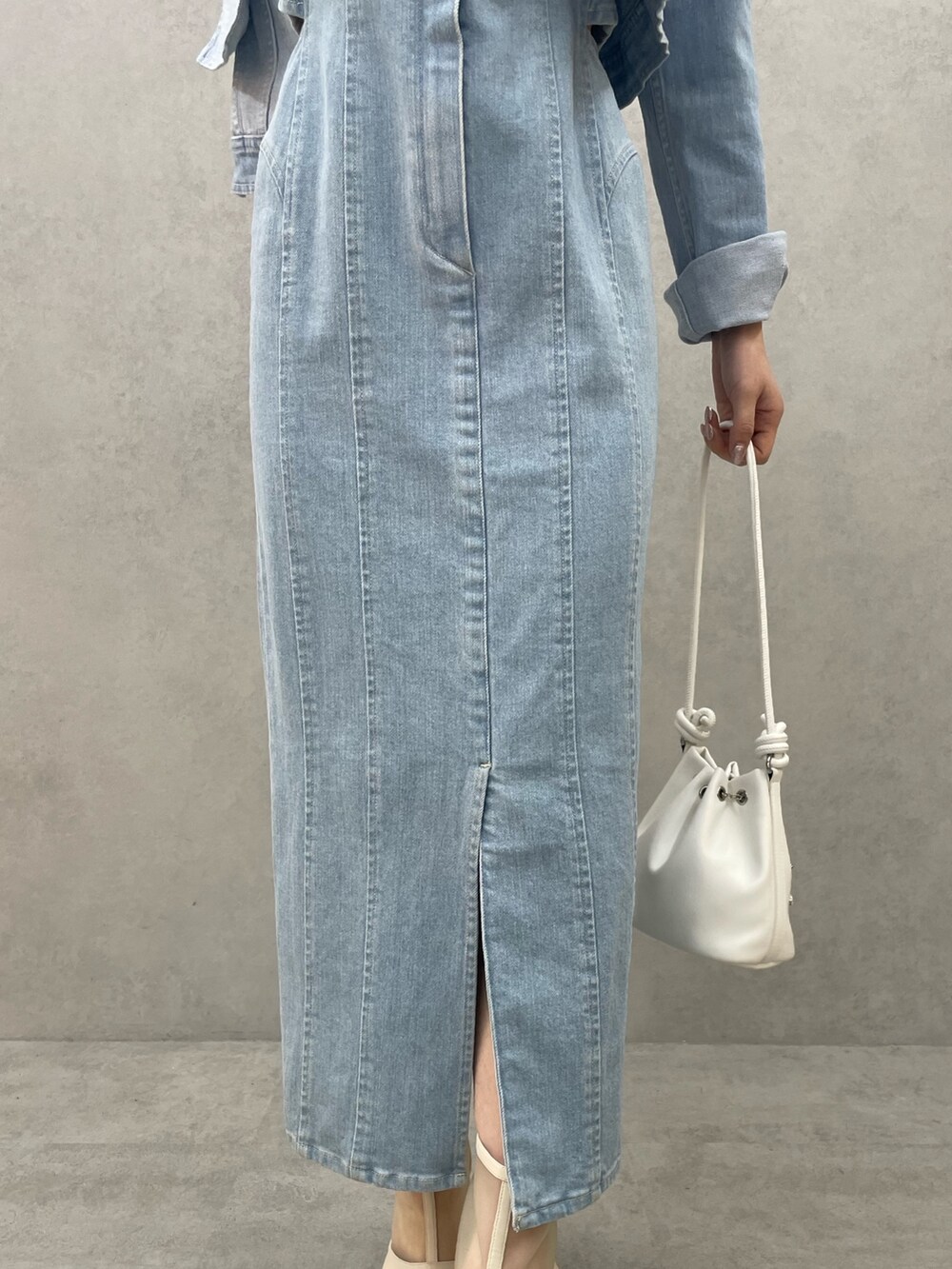 ブルー系のデニムジャケット、ブルー系のワンピース、ホワイト系のハンドバッグを着用したレディースの春コーディネートの7枚目の写真