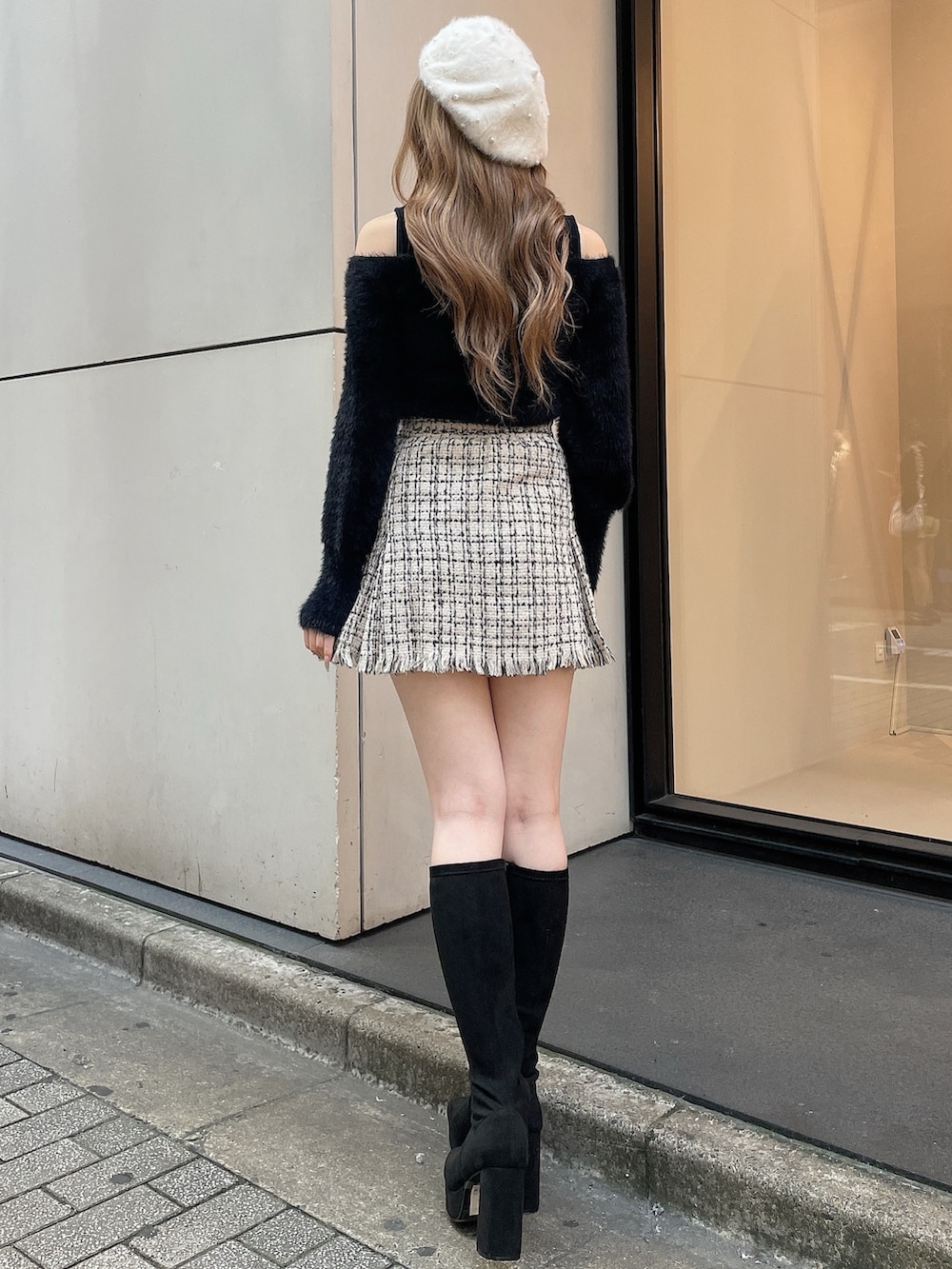 ブラック系のブーツ、ホワイト系のスカート、ブラック系のニット/セーターを着用したレディースの秋コーディネートの3枚目の写真