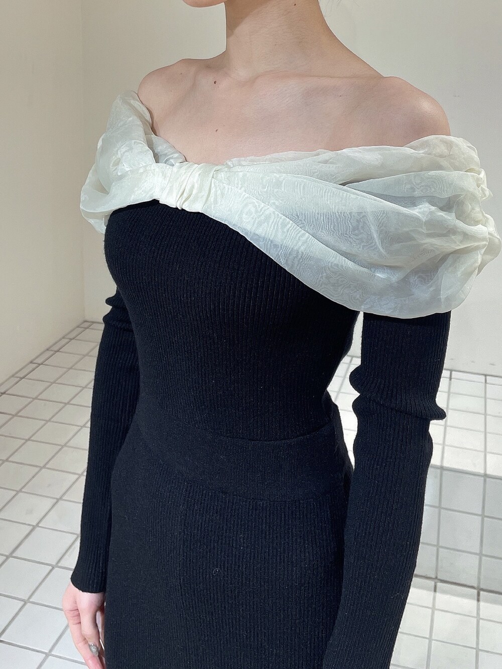 ホワイト系のハンドバッグ、ホワイト系のブーツ、ブラック系のワンピースを着用したレディースの冬コーディネートの5枚目の写真