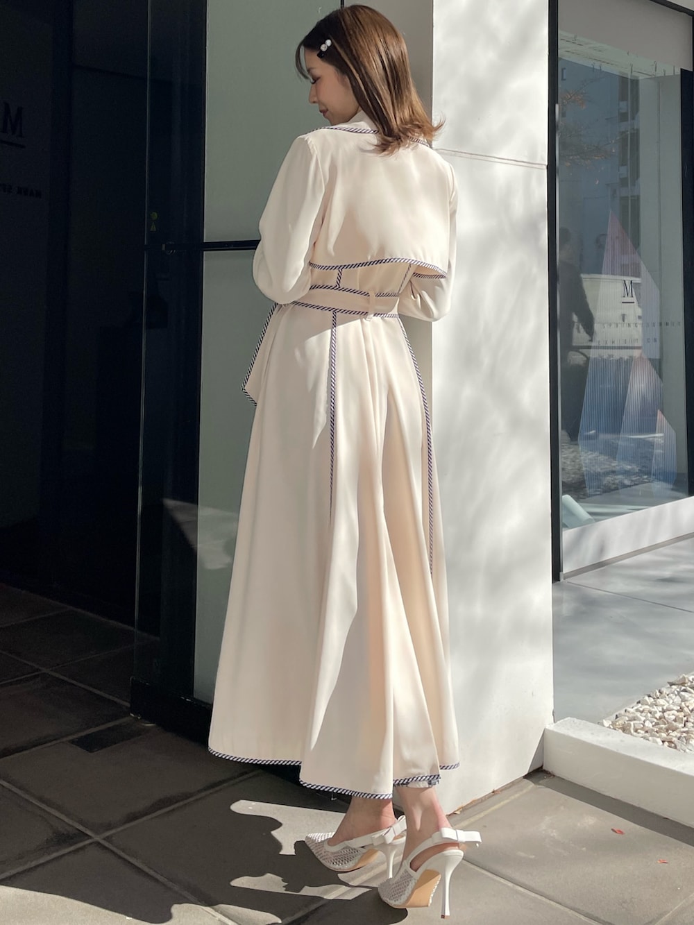 ホワイト系のトレンチコート、ブルー系のワンピース、ホワイト系のパンプスを着用したレディースの冬コーディネートの4枚目の写真