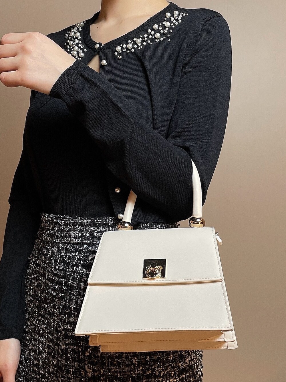 ホワイト系のハンドバッグ、ブラック系のカーディガン/ボレロ、ブラック系のスカートを着用したレディースの冬コーディネートの7枚目の写真