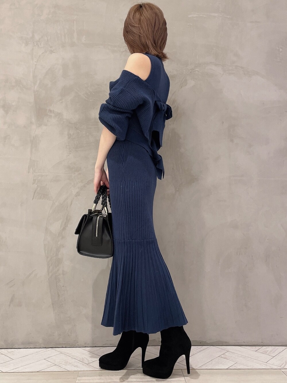 ブルー系のワンピース、ブラック系のブーツ、ブラック系のハンドバッグを着用したレディースの秋コーディネートの3枚目の写真