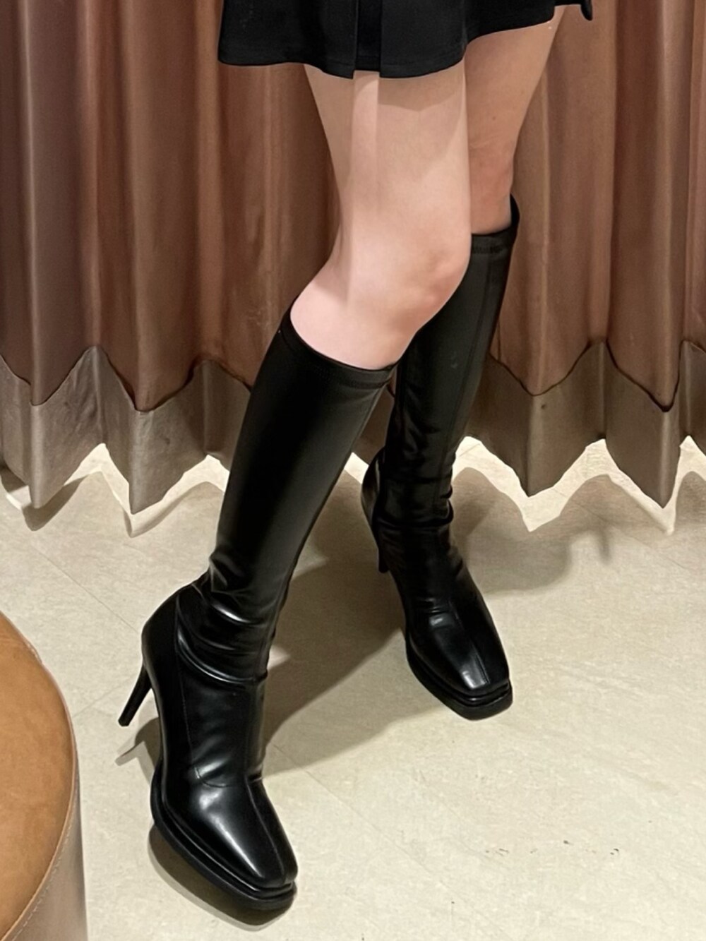 ホワイト系のカーディガン/ボレロ、ブラック系のスカート、ブラック系のブーツを着用したレディースの冬コーディネートの7枚目の写真