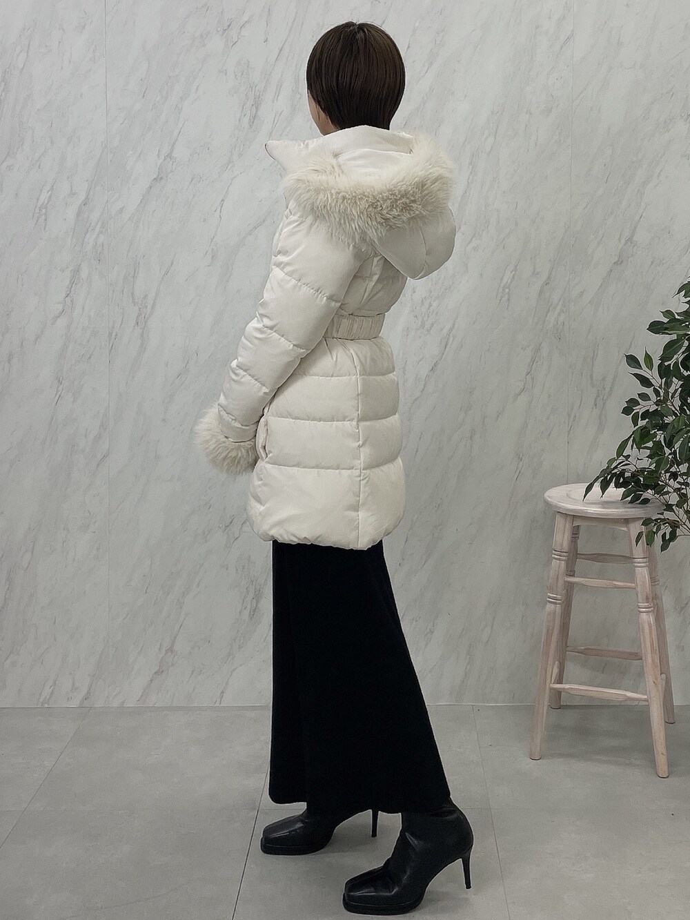 ブラック系のブーツ、ブラック系のワンピース、ホワイト系のダウンジャケット/コートを着用したレディースの夏コーディネートの2枚目の写真