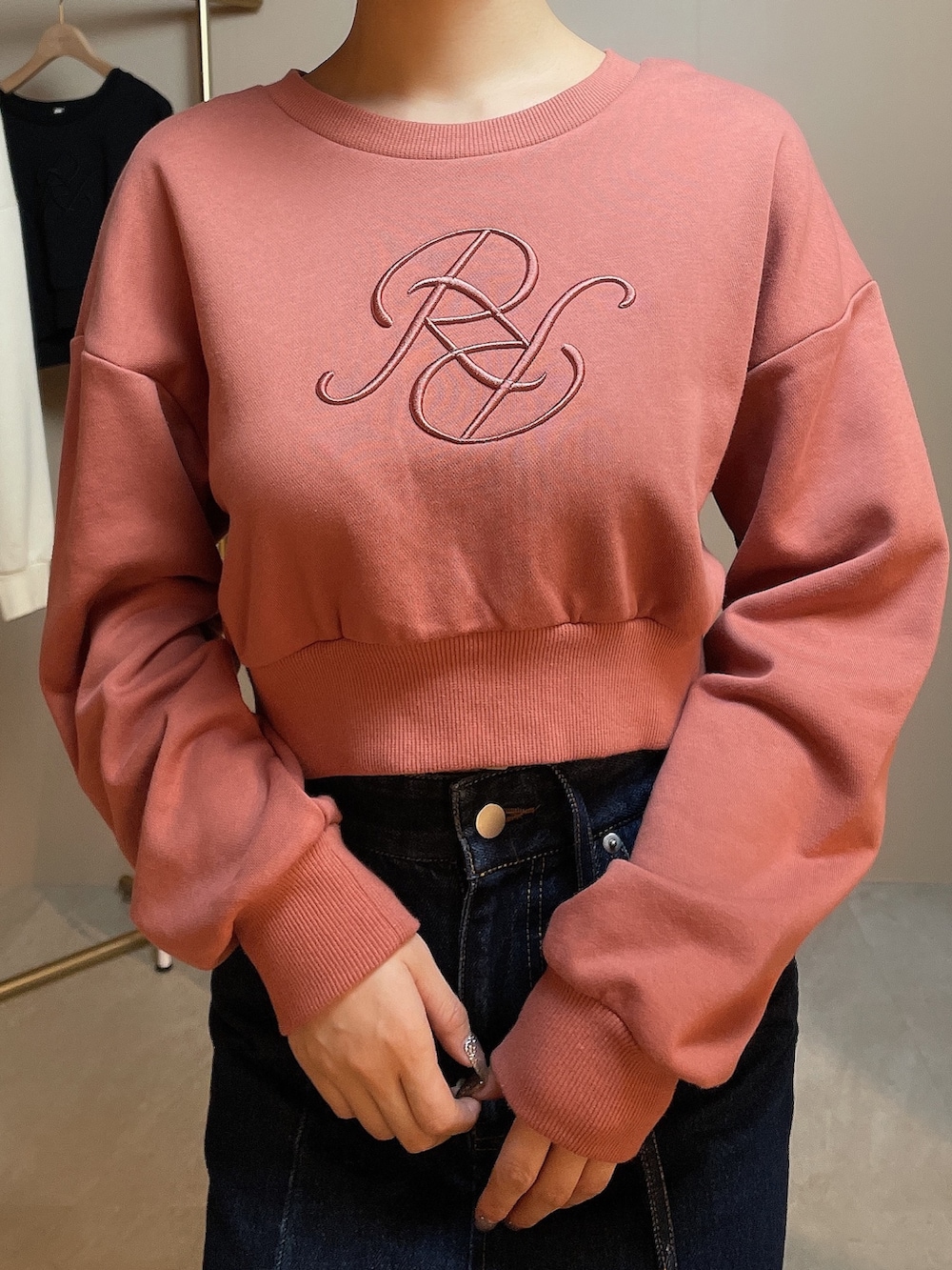 ブラック系のハンドバッグ、オレンジ系のスウェット、ブルー系のデニムスカートを着用したレディースの冬コーディネートの4枚目の写真