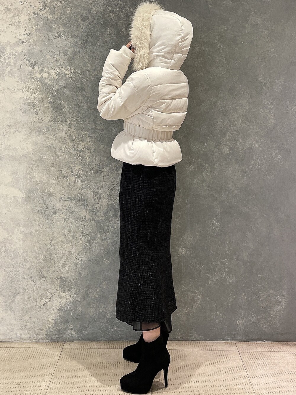 ホワイト系のダウンジャケット/コート、ブラック系のスカート、ブラック系のブーツを着用したレディースの秋コーディネートの4枚目の写真