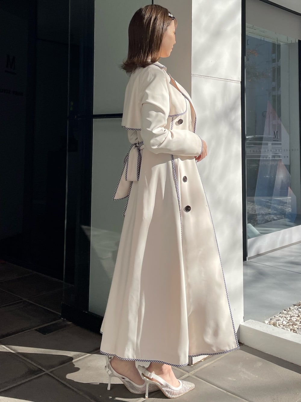 ホワイト系のトレンチコート、ブルー系のワンピース、ホワイト系のパンプスを着用したレディースの冬コーディネートの6枚目の写真