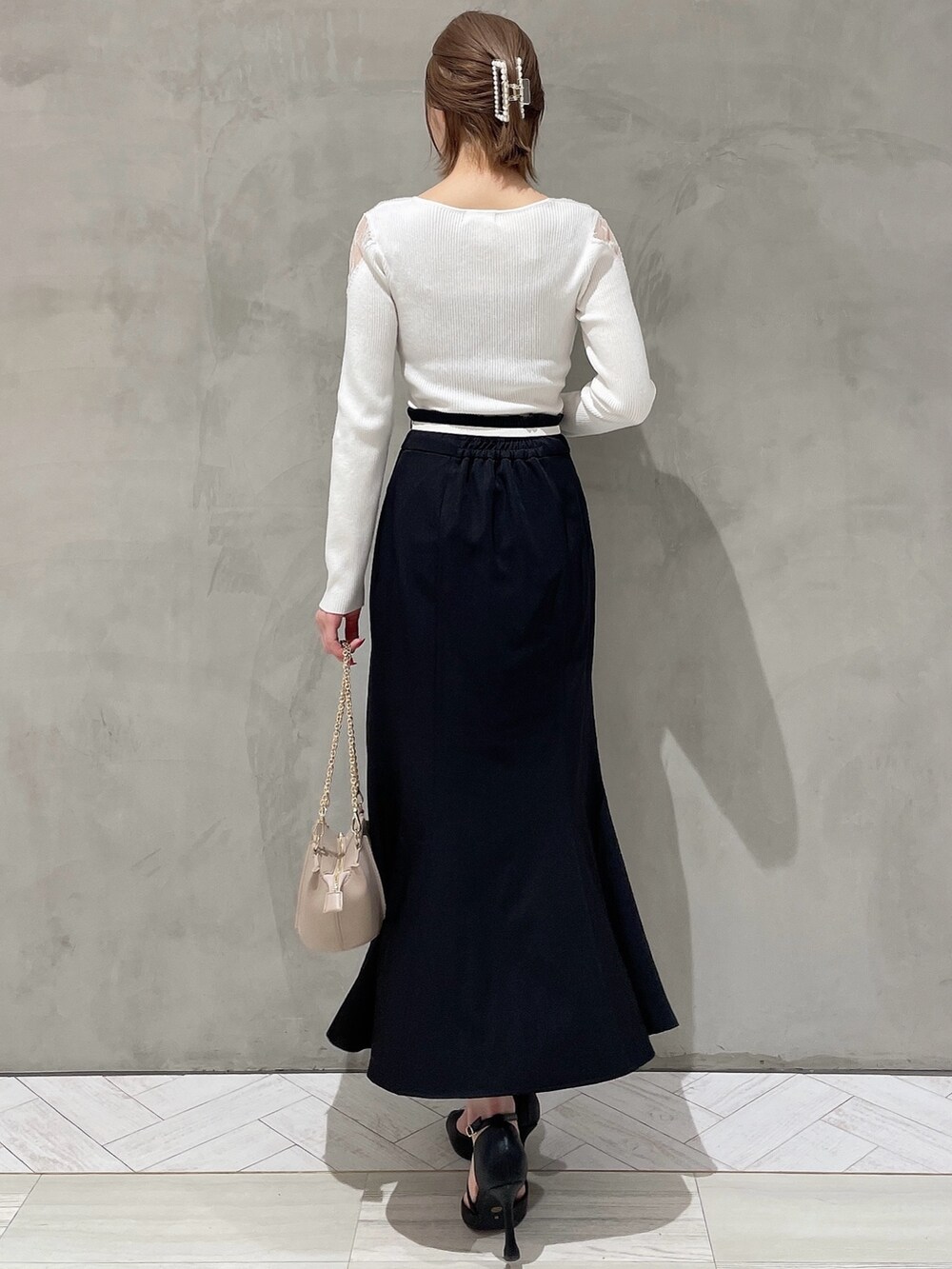 ホワイト系のニット/セーター、ベージュ系のハンドバッグ、ブラック系のスカートを着用したレディースの冬コーディネートの3枚目の写真