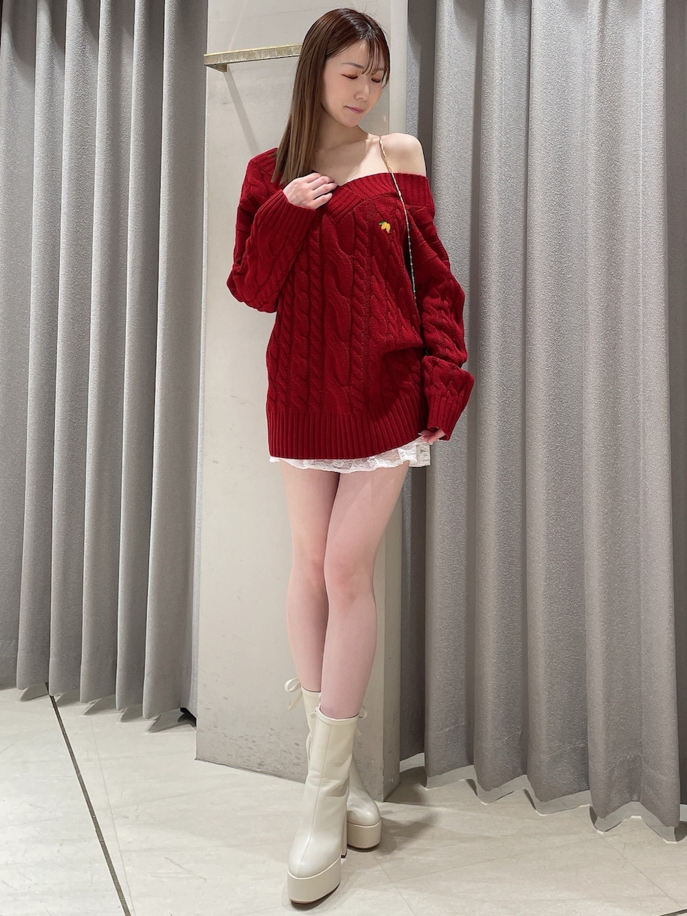 レッド系のニット/セーター、ホワイト系のスカート、ホワイト系のショルダーバッグを着用したレディースの冬コーディネートの5枚目の写真