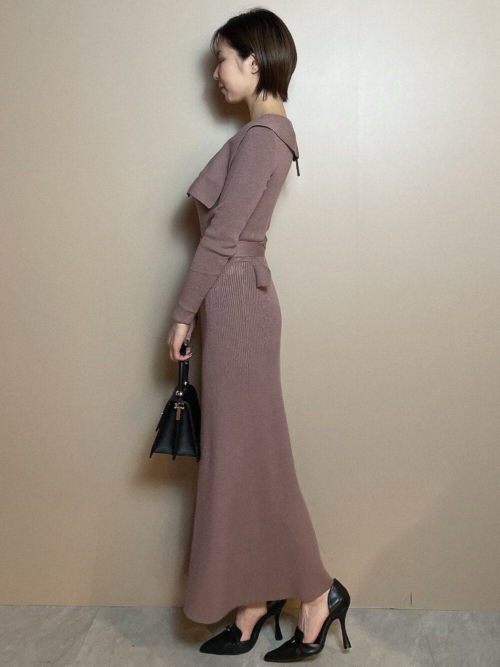 ピンク系のワンピース、ブラック系のハンドバッグ、ブラック系のパンプスを着用したレディースの冬コーディネートの4枚目の写真