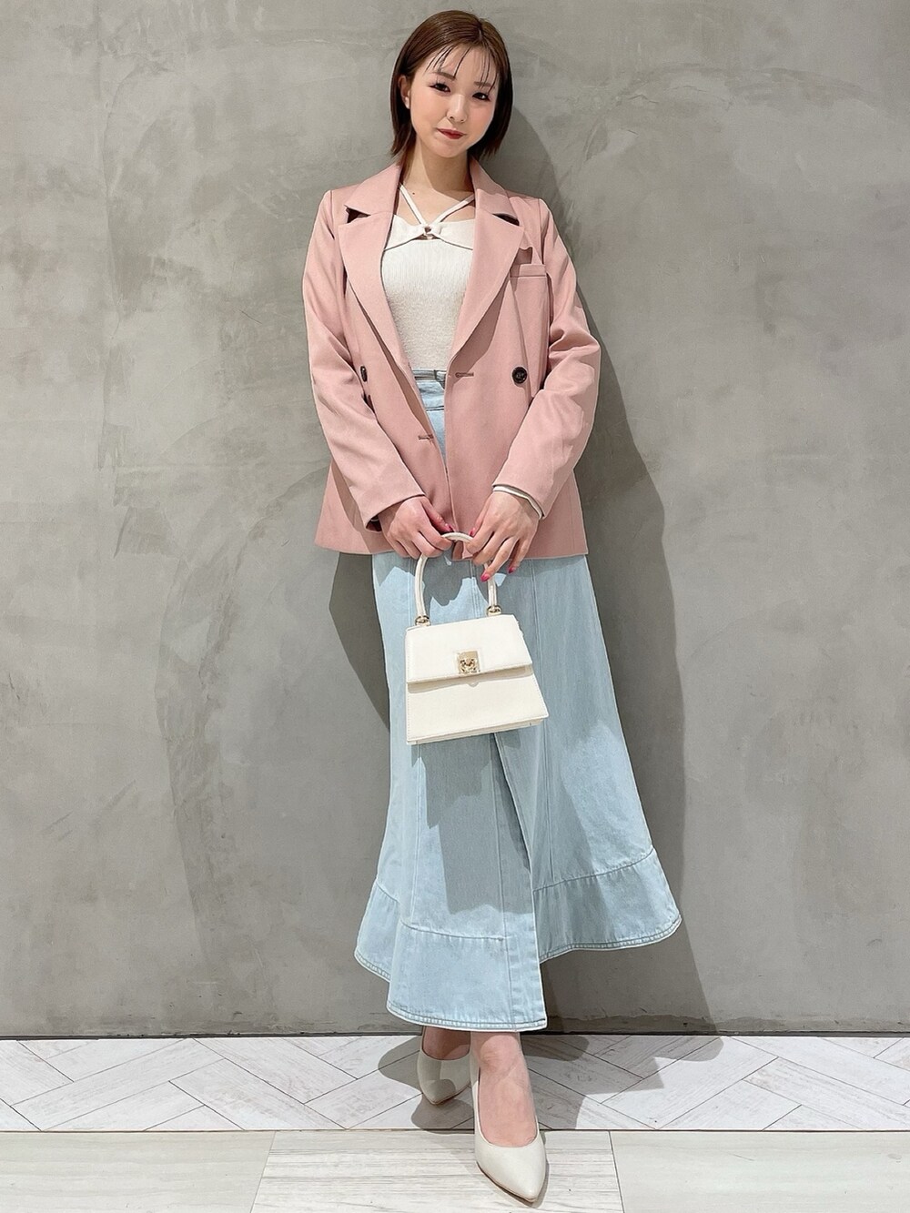 ホワイト系のハンドバッグ、ホワイト系のパンプス、ブルー系のデニムスカートを着用したレディースの冬コーディネートの2枚目の写真