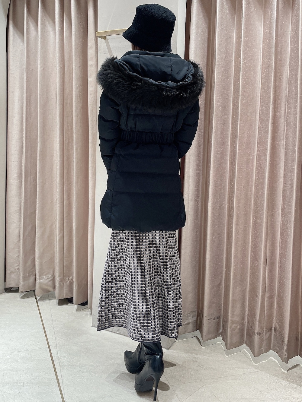 ブラック系のダウンジャケット/コート、ブルー系のワンピース、ブラック系のブーツを着用したレディースの冬コーディネートの3枚目の写真