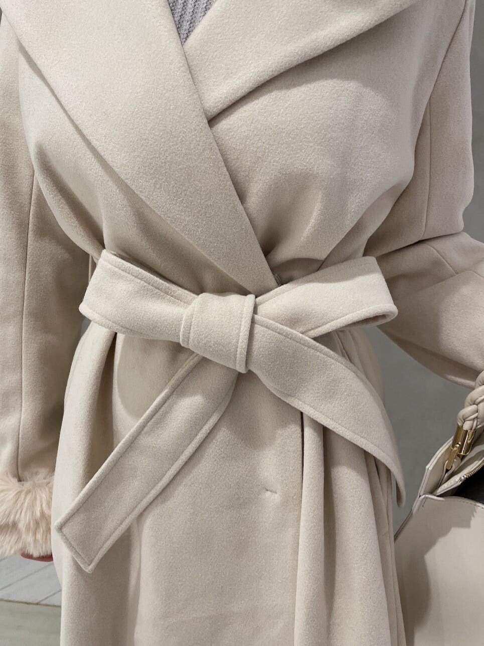 ブラック系のブーツ、ホワイト系のハンドバッグ、ホワイト系のその他アウターを着用したレディースの秋コーディネートの5枚目の写真