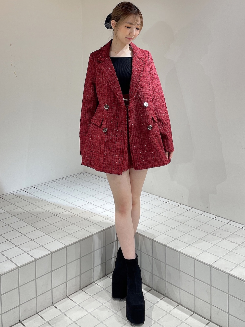 レッド系のテーラードジャケット、レッド系のスカート、ブラック系のニット/セーターを着用したレディースの秋コーディネートの2枚目の写真