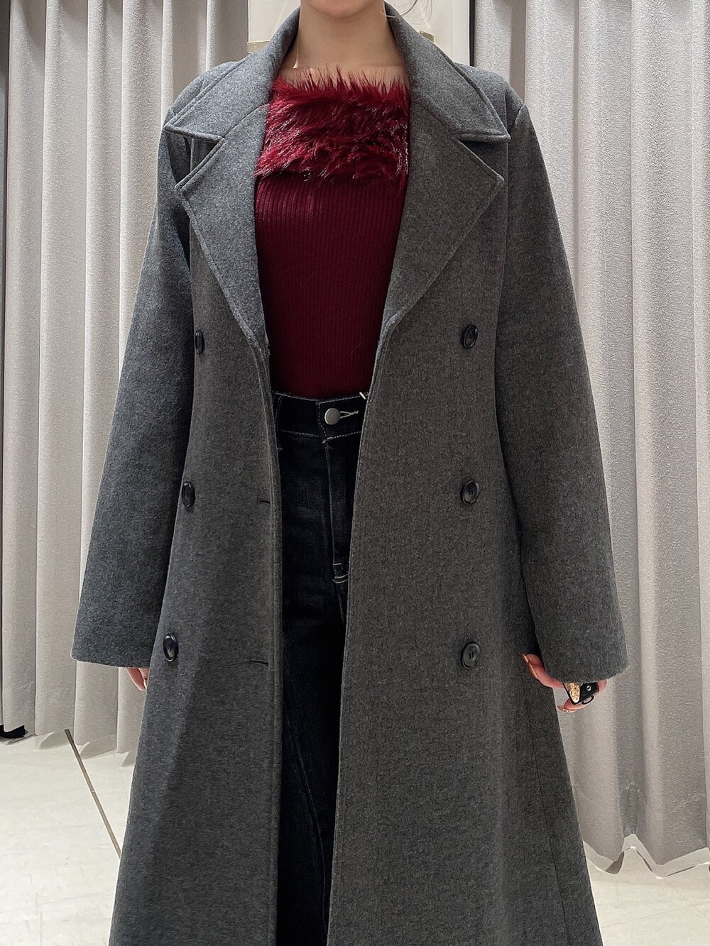 レッド系のニット/セーター、ブラック系のデニムパンツ、ブラック系のブーツを着用したレディースの秋コーディネートの8枚目の写真