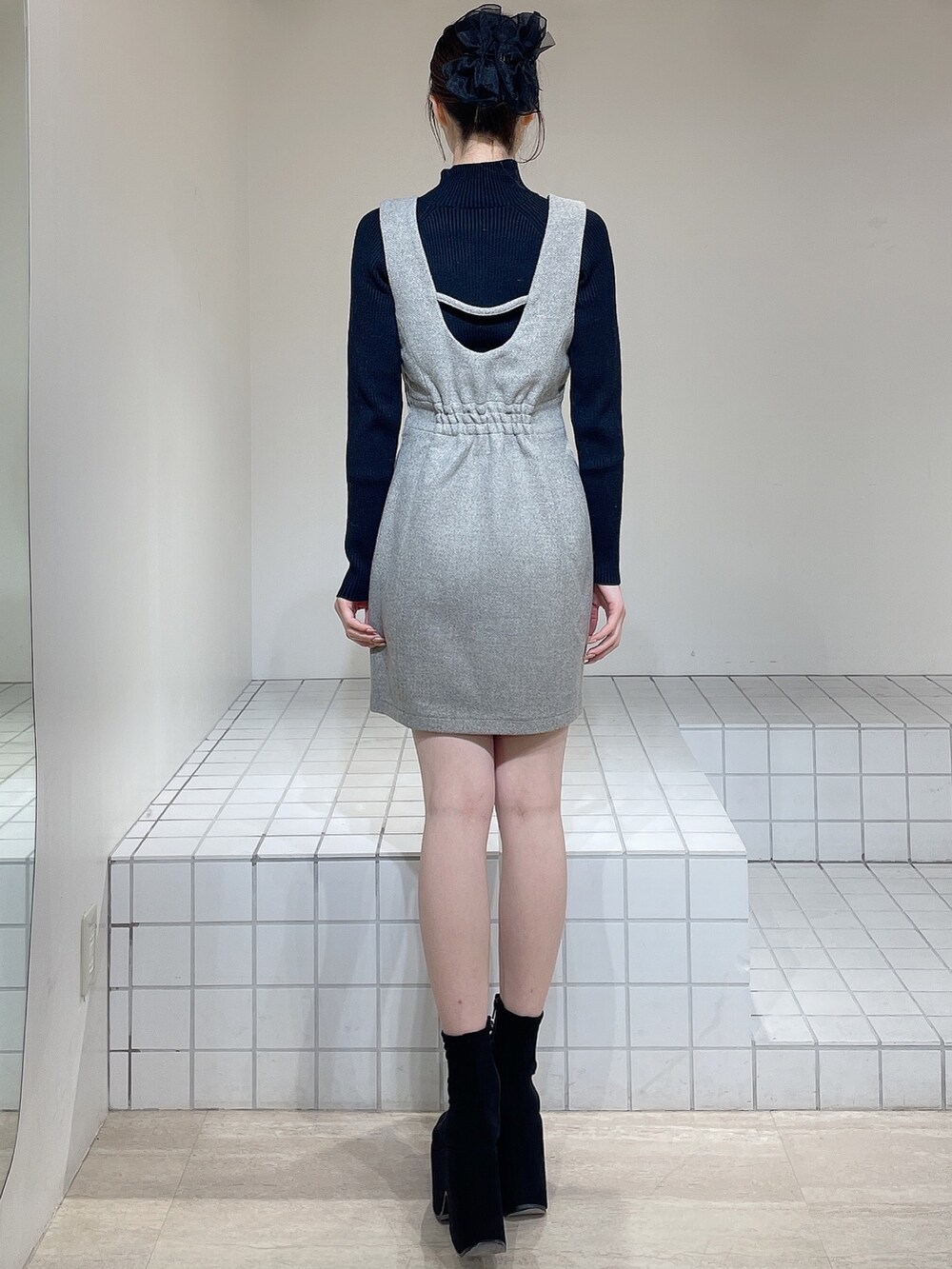 グレー系のその他アウター、グレー系のジャンパースカート、ブラック系のニット/セーターを着用したレディースの冬コーディネートの7枚目の写真